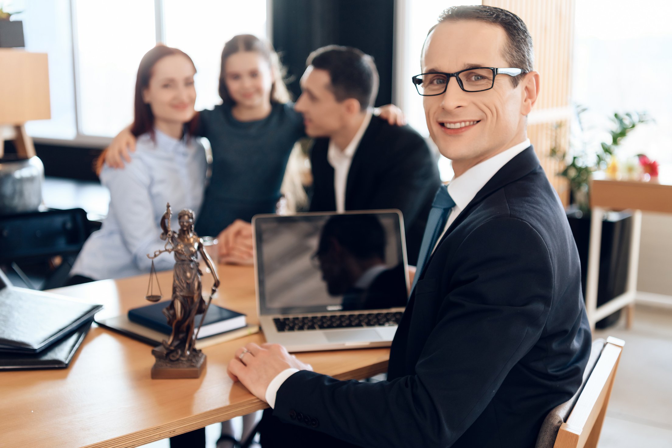 Family lawyer is sitting at table with divorcing family at background.